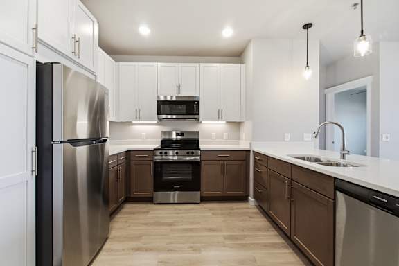 A modern kitchen with a stainless steel refrigerator and wooden flooring.