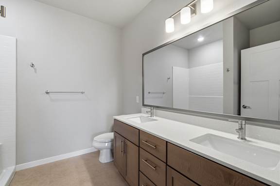 A bathroom with a toilet, sink, and mirror.