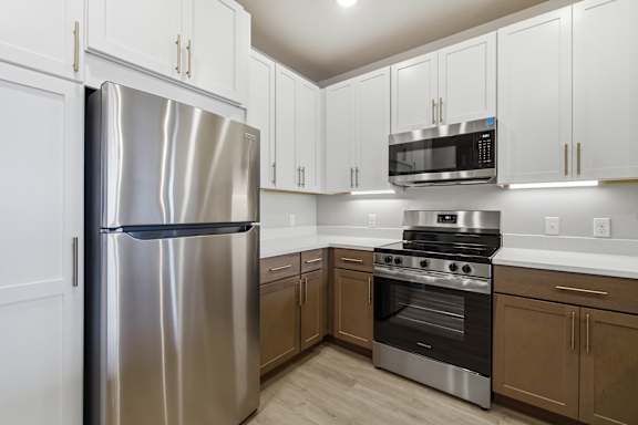 A kitchen with a stainless steel refrigerator, microwave, oven, and cabinets.