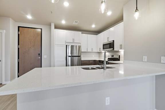 A kitchen with a white countertop and a wooden door.