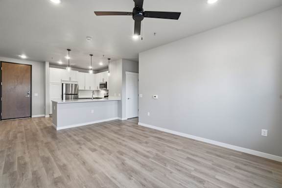 A spacious kitchen and living room with a ceiling fan and lighting fixtures.