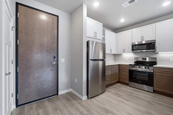 A kitchen with a refrigerator, oven, and microwave.