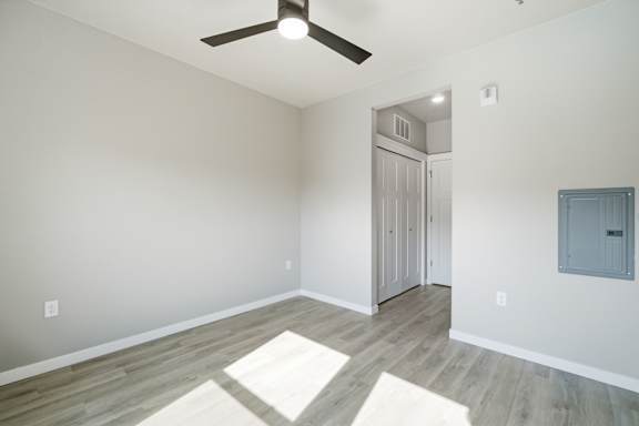 A room with a ceiling fan and a rug on the floor.