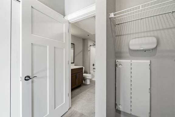 A white door is open to a bathroom with a toilet and a white cabinet.