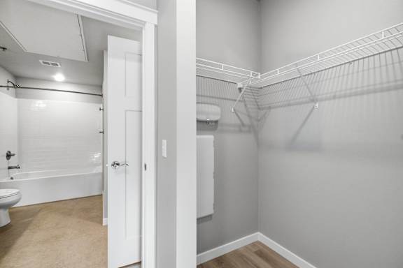 A white bathroom with a toilet, tub, and a walk-in closet.