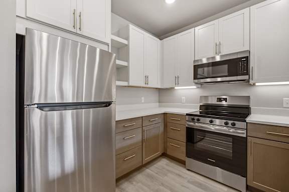 A modern kitchen with a stainless steel refrigerator, microwave, and oven.