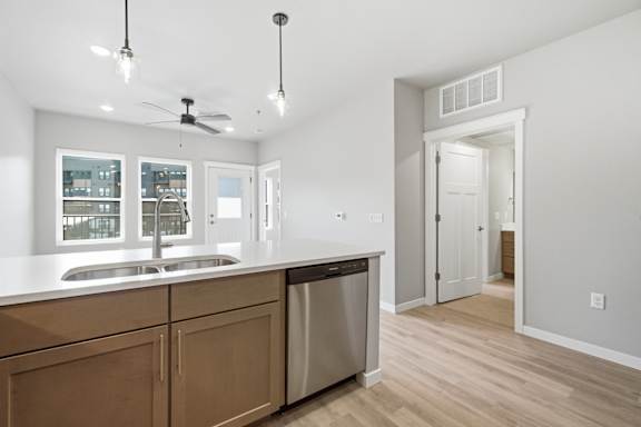 A kitchen with wooden cabinets and a stainless steel dishwasher.
