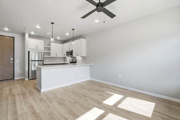 A modern kitchen with a white island and wooden flooring.