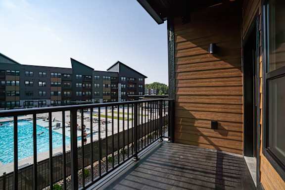 A balcony with a pool in the background.