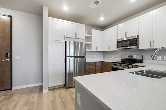 A kitchen with white cabinets and a stainless steel refrigerator.