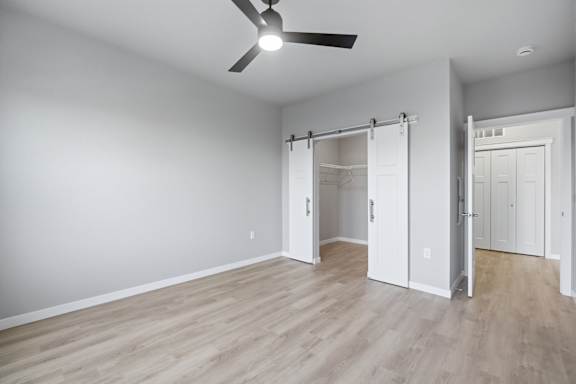 A room with a ceiling fan and sliding doors.