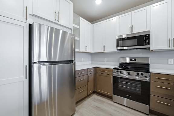 A kitchen with a stainless steel refrigerator, microwave, and oven.