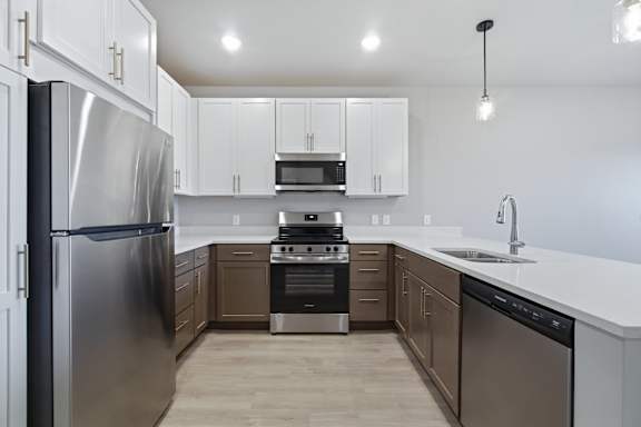 A modern kitchen with a stainless steel refrigerator and wooden flooring.
