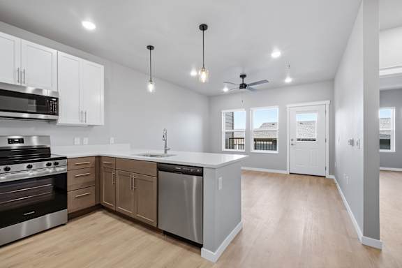 A modern kitchen with wooden floors and stainless steel appliances.