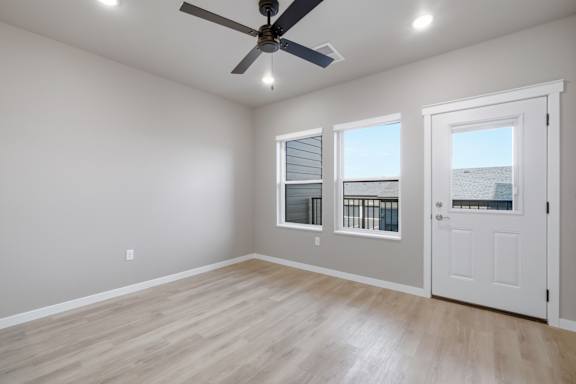 A room with a ceiling fan and two windows.