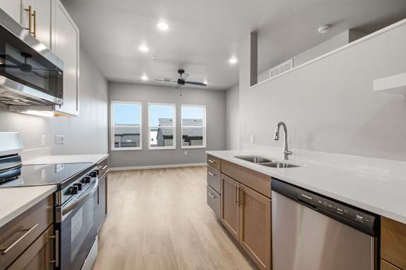 A modern kitchen with wooden floors and stainless steel appliances.