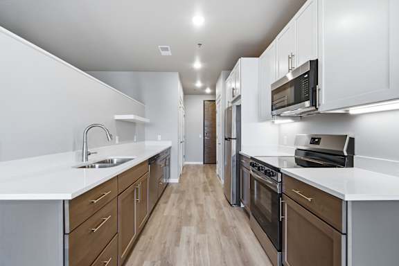 A modern kitchen with white countertops and wooden floors.