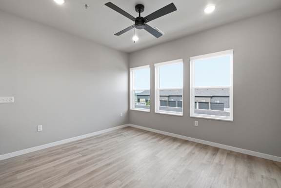 A room with a ceiling fan and three windows.