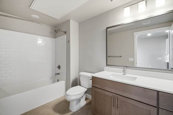 A white toilet sits in a bathroom next to a white bathtub.