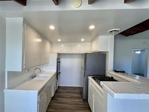 A kitchen with white cabinets and a black refrigerator.