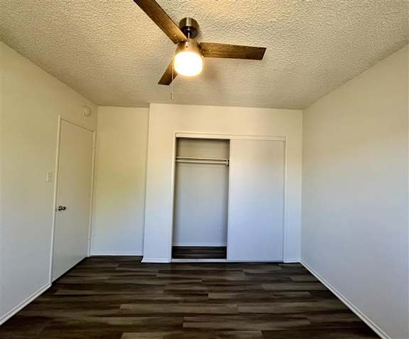 A room with a ceiling fan and wooden flooring.
