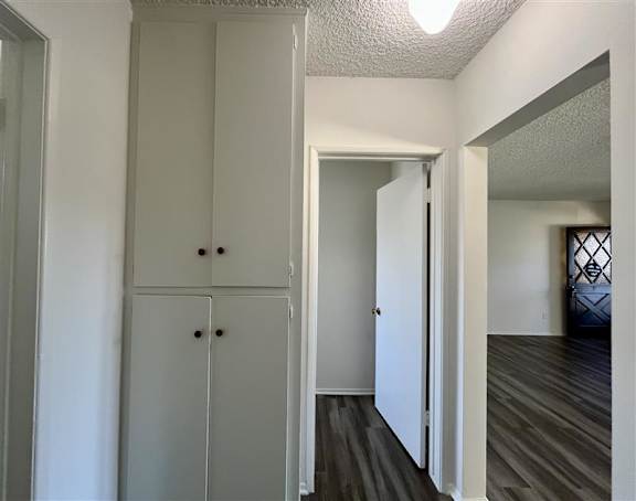 A white cabinet with two doors and two drawers is in a room with wood flooring.
