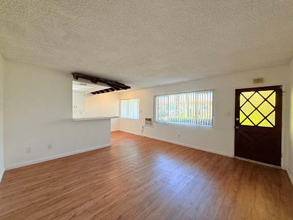 A room with wooden floors and a window with blinds.