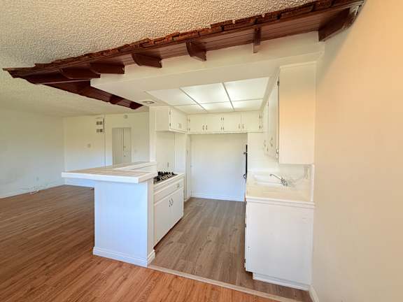 A kitchen with white cabinets and a wooden floor.
