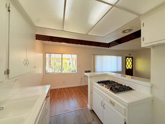 A white kitchen with a wooden floor and a window.