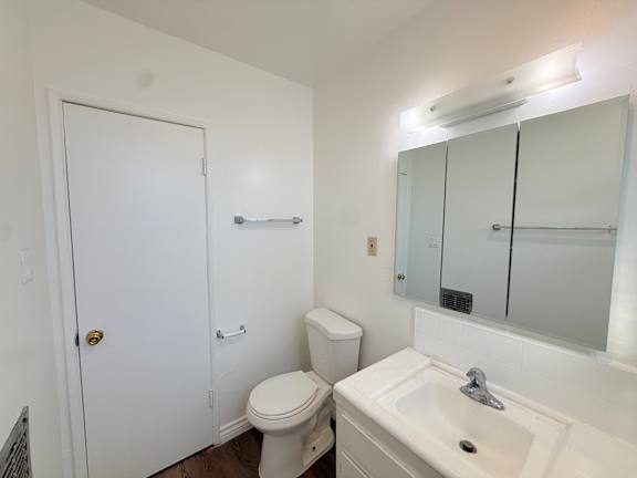 A white bathroom with a toilet, sink, and mirror.