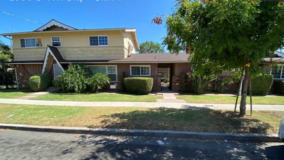 A yellow house with a green tree in front.
