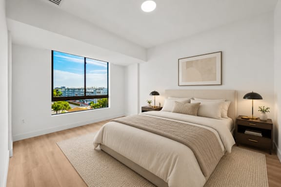 A bedroom with a large bed and a view of the city through the window.
