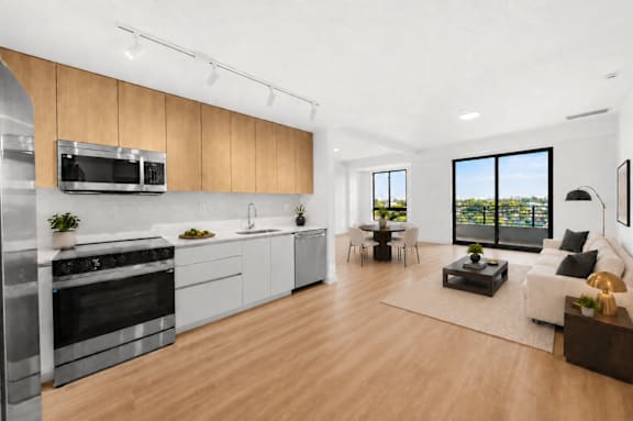 A modern kitchen with wooden floors and stainless steel appliances.