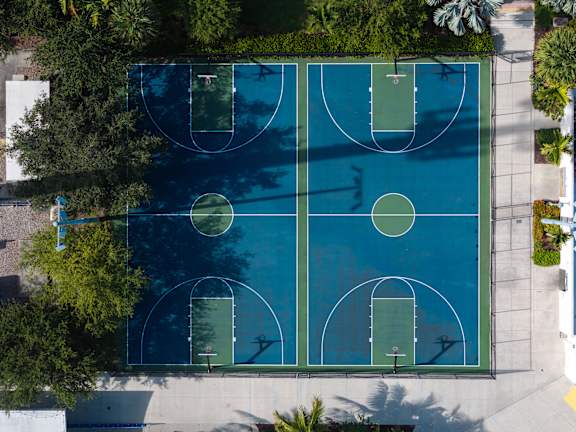 An outdoor basketball court surrounded by trees.