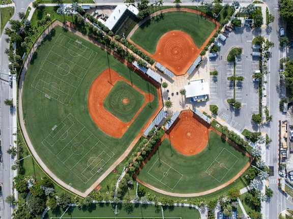 An aerial view of a baseball field surrounded by a parking lot.