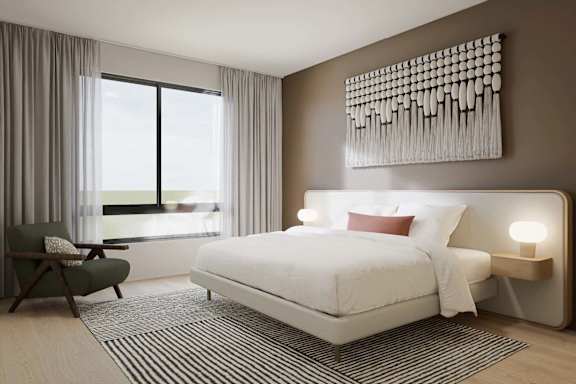 A bedroom with a large bed, a chair, and a wall art.