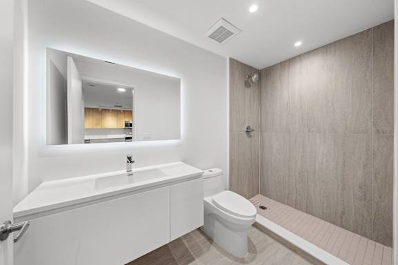 A modern bathroom with a white sink and toilet.