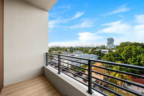 A balcony with a view of a cityscape and trees.