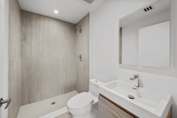 A modern bathroom with a toilet, sink, and mirror.