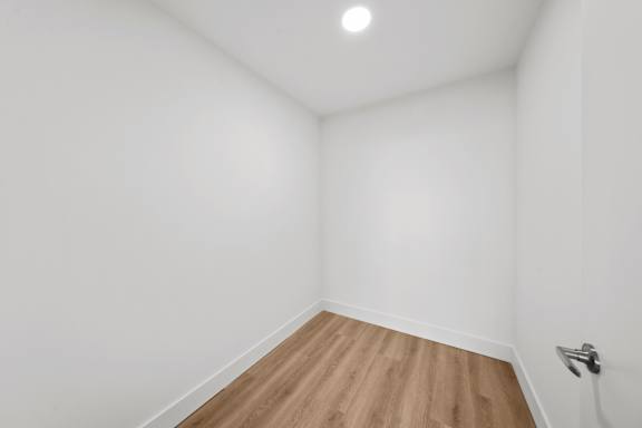 A room with a wooden floor and a light switch on the wall.