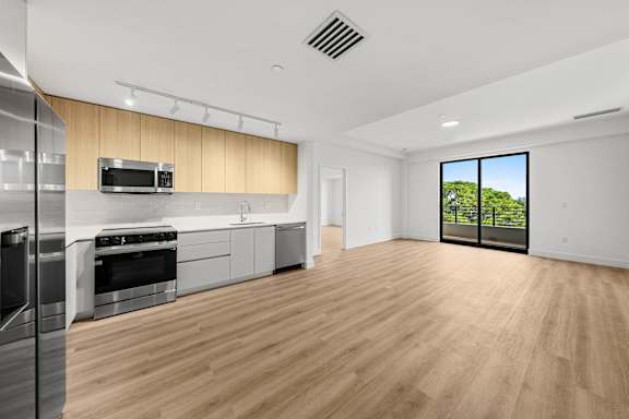 A modern kitchen with wooden floors and stainless steel appliances.