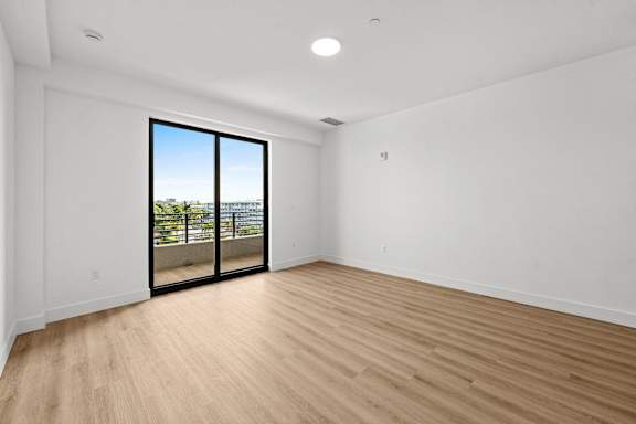A room with a sliding glass door leading to a balcony.