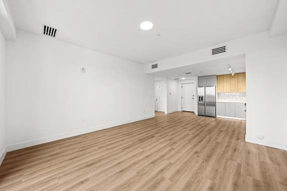 A large empty room with wooden flooring and white walls.