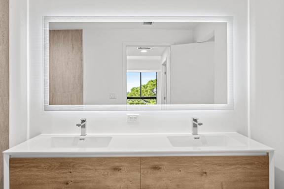 A bathroom with two sinks and a large mirror.