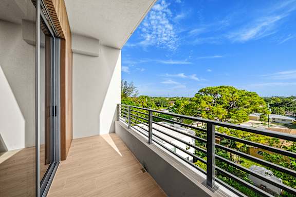A balcony with a metal railing and a view of a tree-filled landscape.