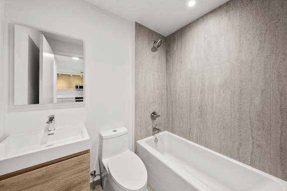 A white toilet sits next to a white bathtub in a bathroom.