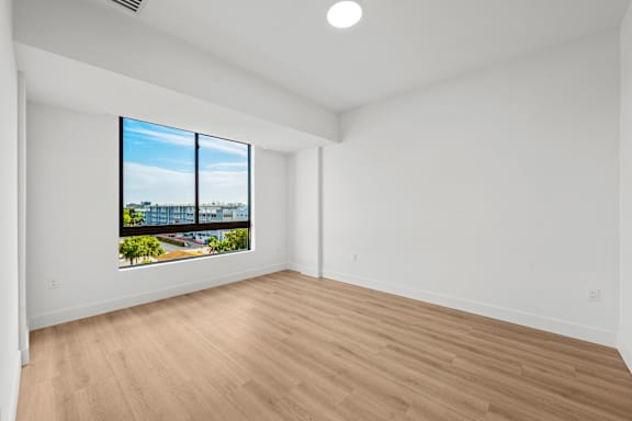 A room with a large window and wooden flooring.