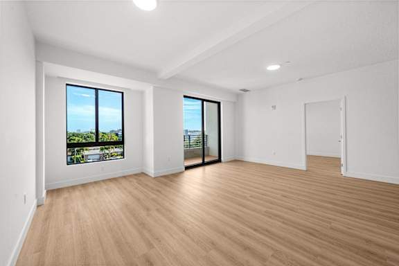 A room with wooden floors and a view of the city through the windows.