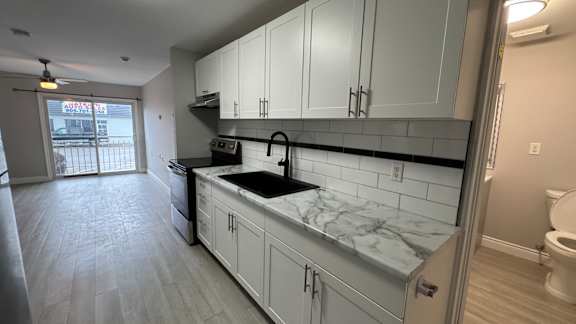 A kitchen with white cabinets and a black countertop.