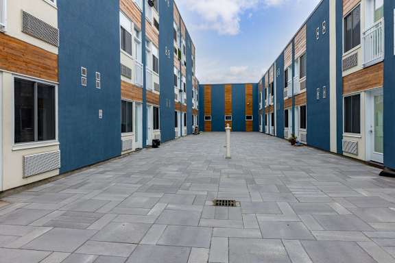 A long, narrow courtyard between two buildings with blue and white walls.